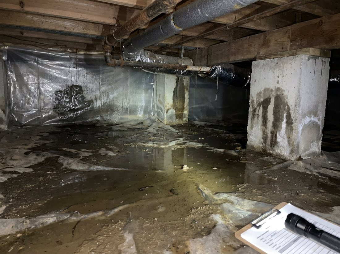 Damp crawlspace with standing water on the vapor barrier