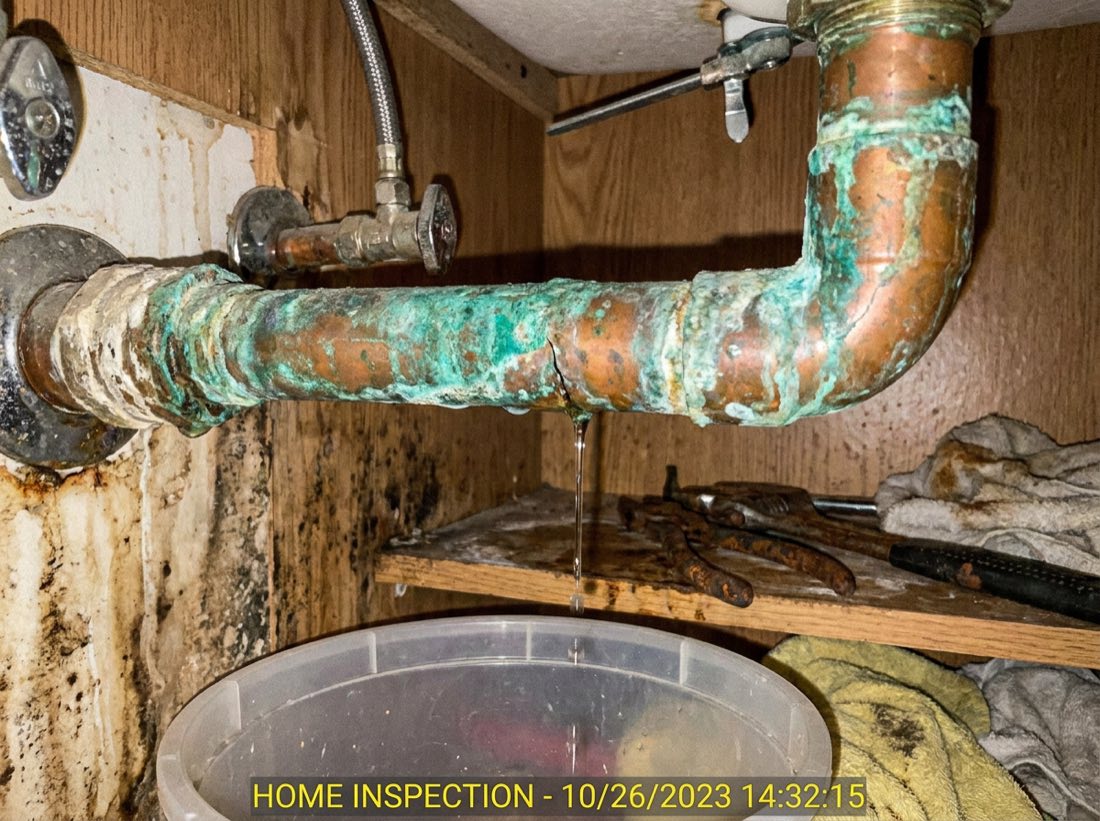 Corroded, leaking copper pipe under a bathroom sink